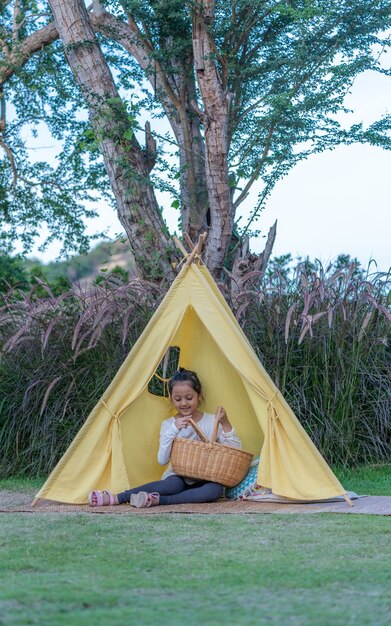 Carpa amarilla con linda niña en su interior en la naturaleza