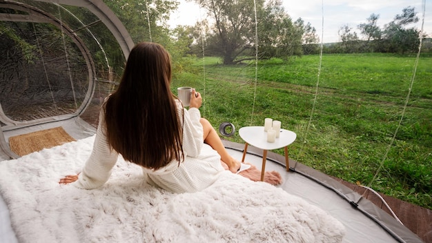 Carpa burbuja transparente y mujer en glamping