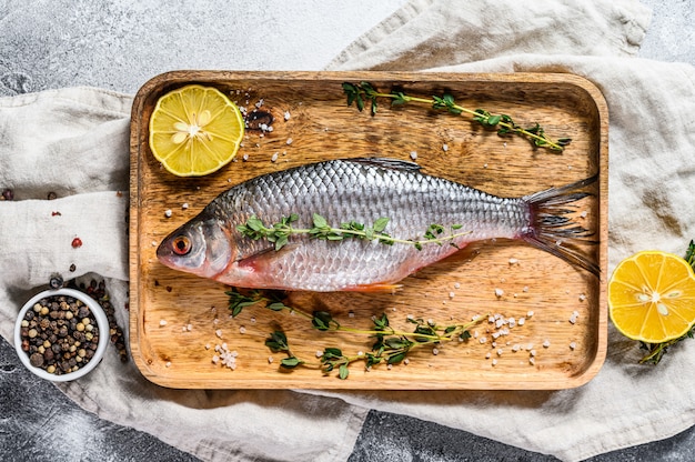 Carpa crucian cruda en una bandeja de madera. Pescado orgánico de río. Vista superior