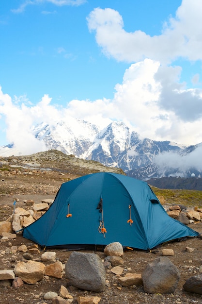 Carpa y montañas con cielo azul nublado en el fondo