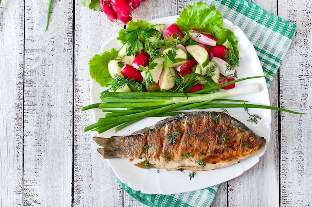 Carpa de pescado frita y ensalada de verduras frescas