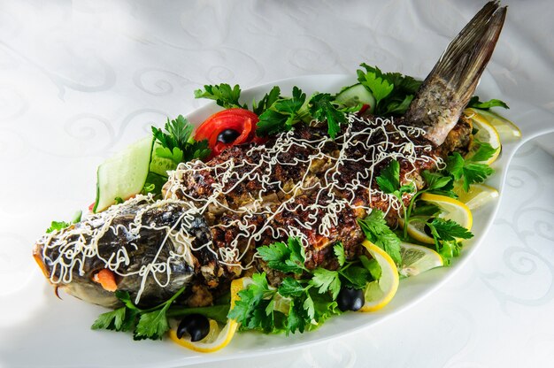 Carpa rellena servida con cebolla frita y verduras.