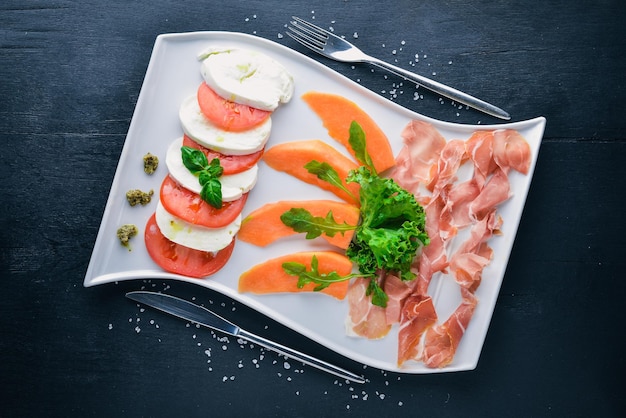 Carpaccio com tomate e queijo mussarela Em um fundo de madeira Vista superior Espaço livre para texto