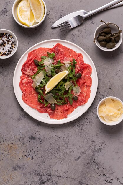 Carpaccio de carne marmoreada com rúcula, alcaparras, limão e queijo parmesão