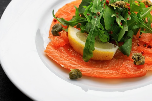 Carpaccio de salmão em prato branco com limão e ervas