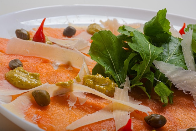 Carpaccio de salmão servido com rúcula e alcaparras