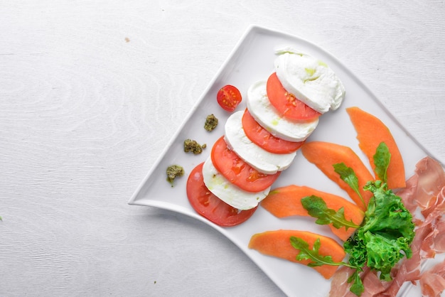 Carpaccio mit Tomaten und Mozzarella-Käse Auf einem hölzernen Hintergrund Ansicht von oben Freier Platz für Text