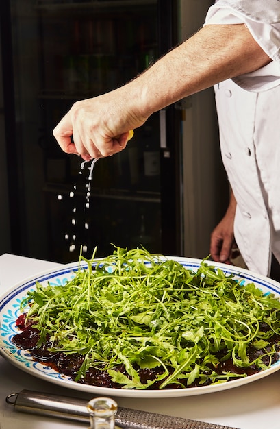 Carpaccio de remolacha, Chef vierte limón sobre carpaccio de remolacha con salsa y hierbas