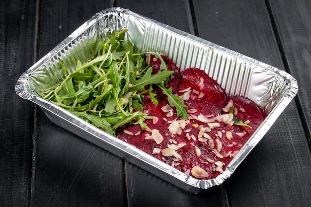 Carpaccio de remolacha con virutas de maní y rúcula en recipientes sobre un fondo oscuro Dieta para llevar y comida saludable