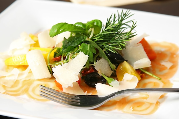 Carpaccio de salmón con algunos extras y tenedor en la mesa