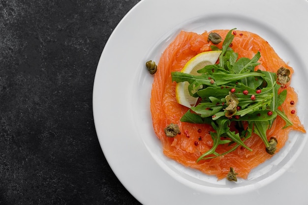 Carpaccio de salmón en un plato con limón sobre hormigón