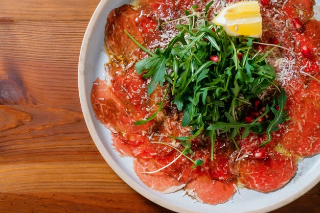 Carpaccio de ternera con primer plano de limón y hierbas Carne fría italiana