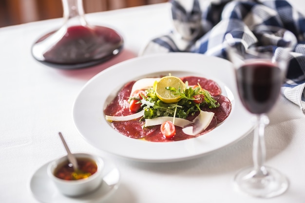 Carpaccio con tomates rúcula parmesano limón y vino tinto.