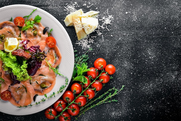 Carpaccio von Fisch, Gemüse, Käse, Gewürzen, Holzhintergrund. Ansicht von oben. Freiraum.