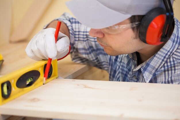 Carpenter usando a nivel de burbuja para trazar una línea recta