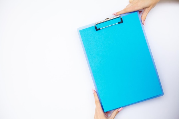 Foto carpeta en blanco con la mano de papel azul que sostiene la carpeta y la pluma en el espacio de copia de fondo blanco