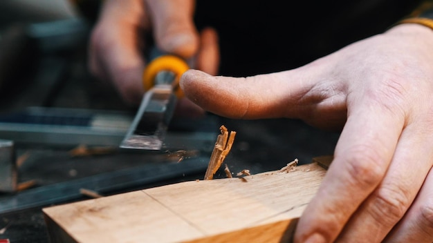 Carpintaria na oficina um marceneiro cortando o recesso no bloco de madeira com um cinzel