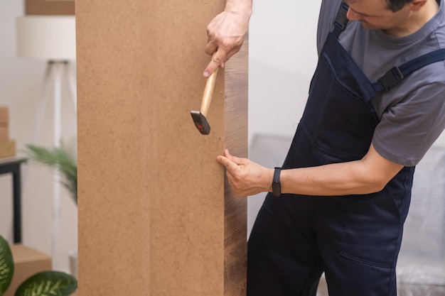 Carpinteiro de negócios de fabricação de móveis martelando pregos no painel de madeira na parte de trás do guarda-roupa