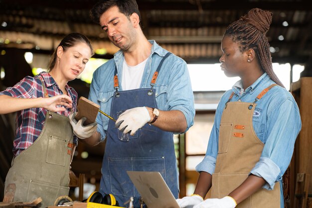 Foto carpinteiro e seu assistente trabalhando juntos em uma oficina de carpintaria