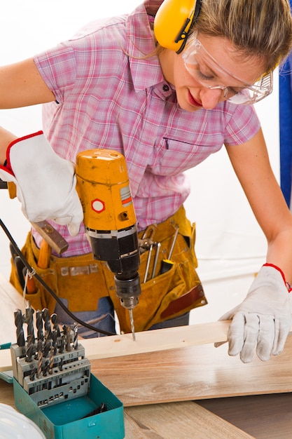 Foto carpinteiro feminino no trabalho usando a máquina de perfuração de mão