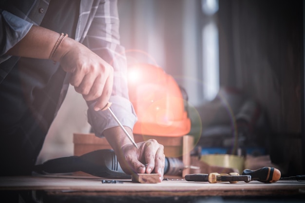 Carpinteiro habilidoso cortando um pedaço de madeira em sua oficina de carpintaria usando uma serra de mão