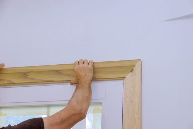 Carpinteiro instalando nas molduras das portas, pregando o acabamento da moldura