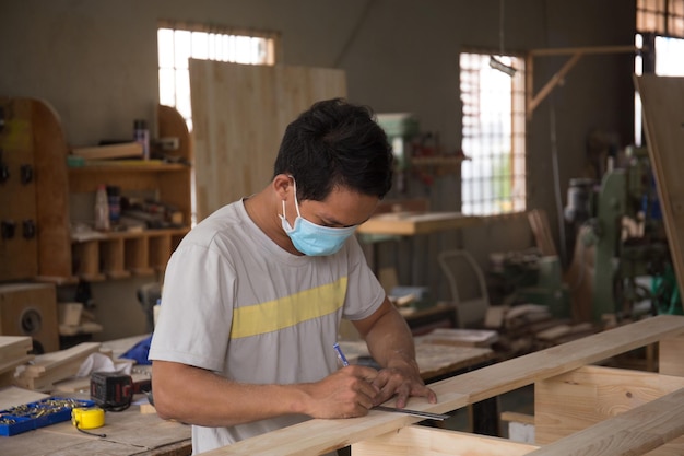 Carpinteiro medindo placa de madeira com régua com escala na oficina.