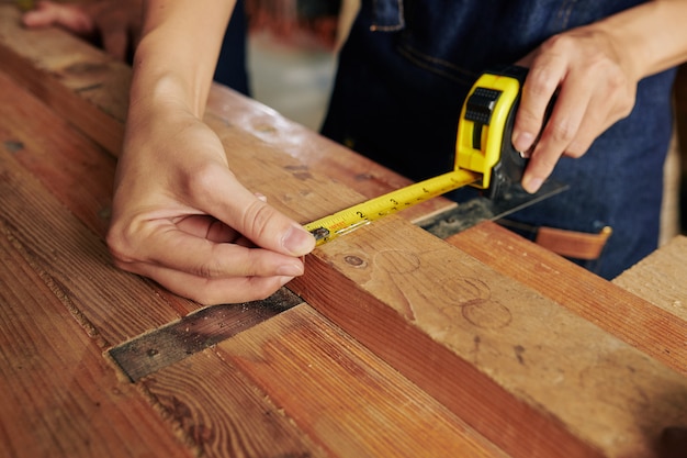 Carpinteiro medindo prancha de madeira