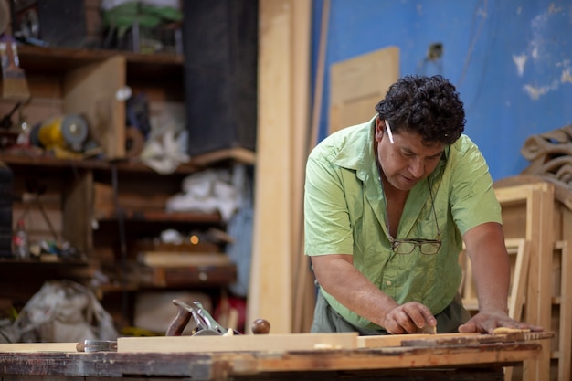 Carpinteiro mexicano trabalhando em sua oficina, lixando