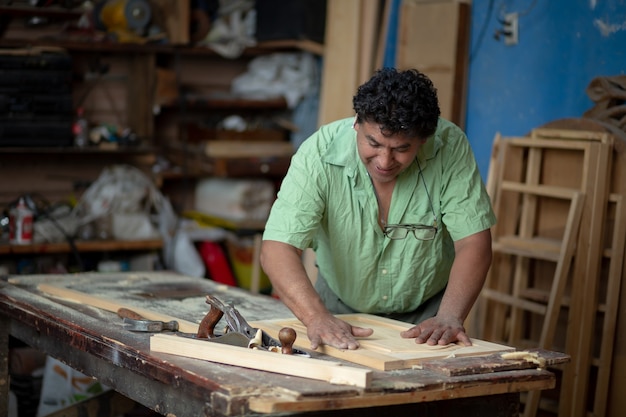 Foto carpinteiro mexicano trabalhando em sua oficina, lixando