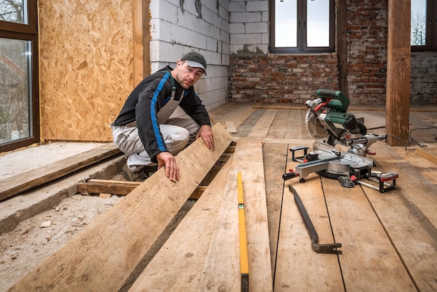 Carpinteiro profissional carpinteiro faz piso de madeira usando serra de esquadria