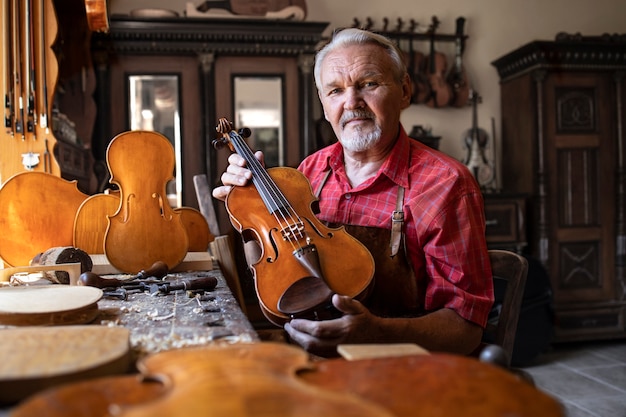 Carpinteiro sênior mostrando o instrumento de violino que ele criou.