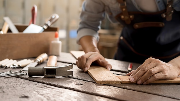 Foto carpinteiro, trabalhando com equipamentos na mesa de madeira na carpintaria. mulher trabalha em uma carpintaria.