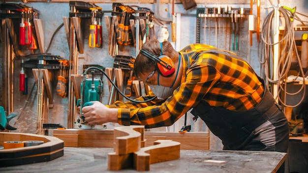 Carpintería interior un carpintero pule el detalle de madera con un esfuerzo en el taller