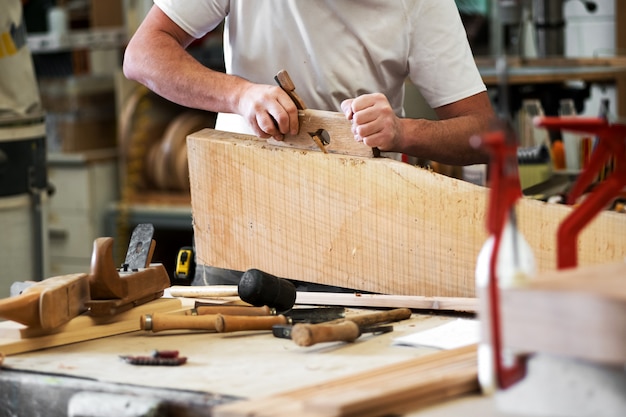 Carpintero cepillando un bloque de madera en el taller