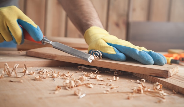 Carpintero con cincel en tablón de madera.