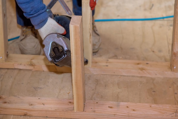 Un carpintero para clavar vigas de madera usando un martillo neumático en el sitio de construcción