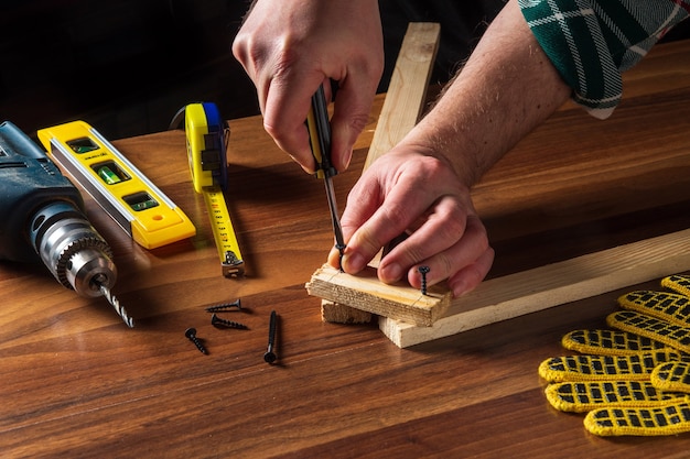 El carpintero conecta las tablas de madera con un destornillador y un tornillo.