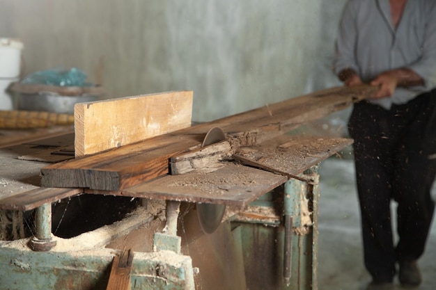 Carpintero cortando un tablón de madera con una máquina de carpintería