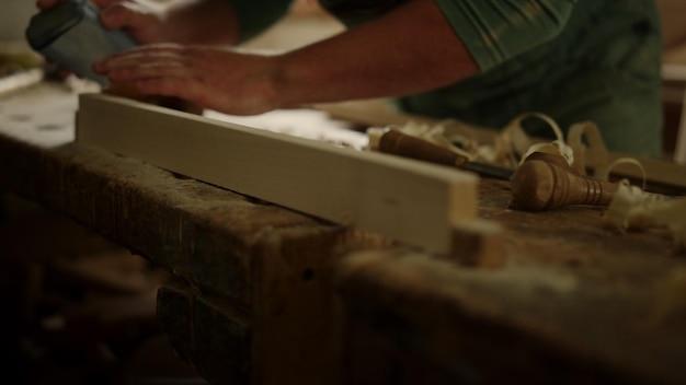 Un carpintero desconocido usando papel de lija en un taller de carpintería Un trabajador de madera comprobando la suavidad de la madera en el estudio Un artesano no reconocido preparando una tabla de madera para un producto en el interior