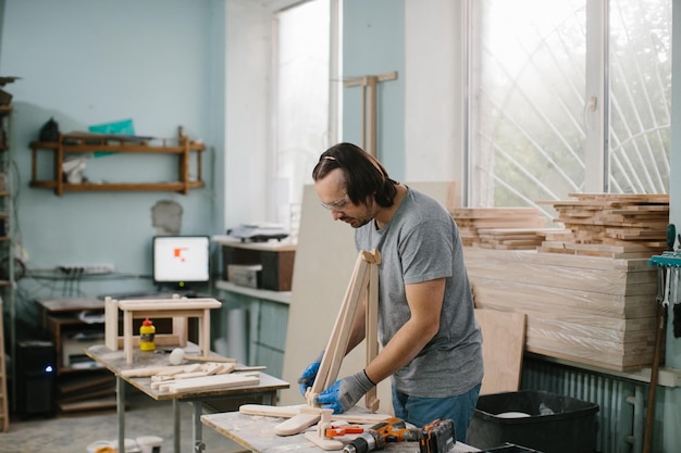 Un carpintero fabrica juguetes de madera en un taller de carpintería Fabricación de un carrusel de cama