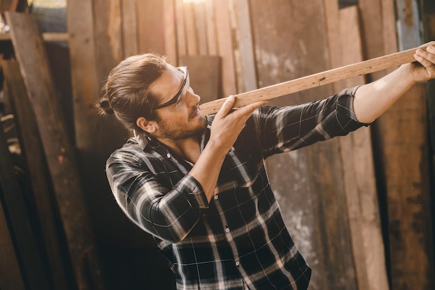 El carpintero hombre trabajador de la madera haciendo muebles Maestro de artesanía en madera macho mirando el panel de madera