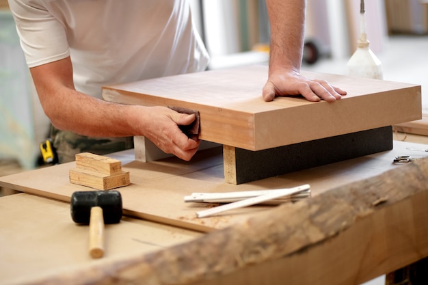 Carpintero lijando un bloque de madera manualmente