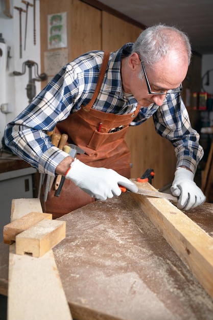 Carpintero limando un tablón de madera en su taller