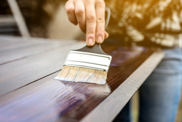 Un carpintero de madera aplica una capa protectora de barniz transparente