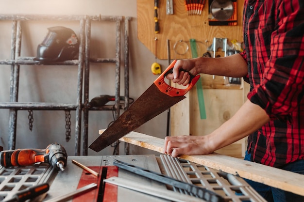 Carpintero masculino caucásico cortando madera mientras trabajaba en el taller