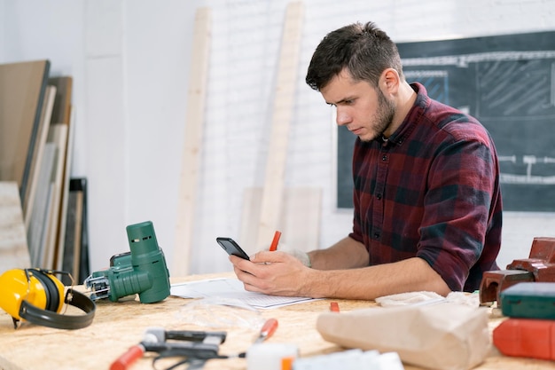 Carpintero masculino positivo en delantal para seguridad en el trabajo satisfecho con buenos comentarios sobre su fabricación