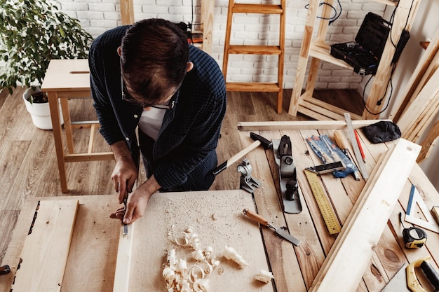 Carpintero de mediana edad trabajando en un taller con cincel y martillo
