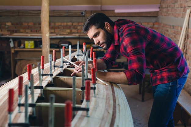 Carpintero montando una nueva canoa de madera de su propio diseño