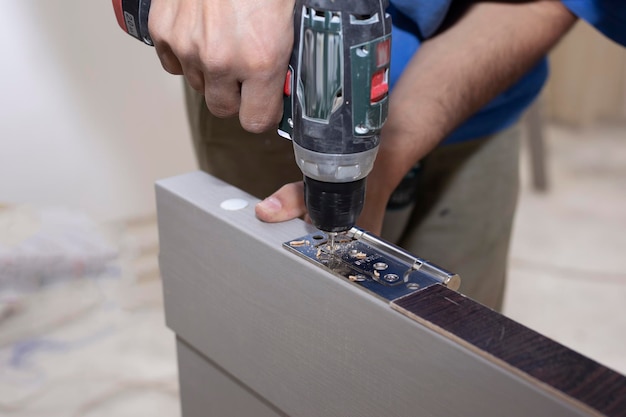 Un carpintero perfora un agujero en una tabla de madera con un taladro eléctrico